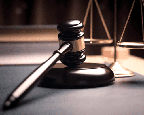 A wooden gavel rests beside balanced golden scales of justice on a courtroom desk. The image symbolizes fairness and due process in California eminent domain law, illustrating property owners’ rights when determining which types of property are exempt from government seizure in Los Angeles.