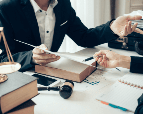 Attorney reviewing documents and discussing terms with a client across a desk, with legal books and a gavel nearby, representing negotiation of condemnation offers and eminent domain compensation in Los Angeles, California.