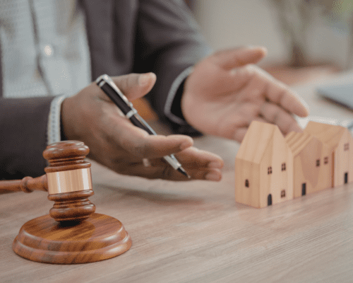 Judge’s gavel and model homes on a desk with a person gesturing, representing mechanics liens, contractor disputes, and commercial property protection in Los Angeles