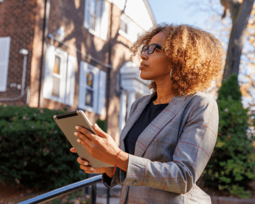 Property appraiser or professional reviewing a residential building with a tablet, representing property valuation, fair market value analysis, and the role of appraisers in Los Angeles condemnation and eminent domain cases.